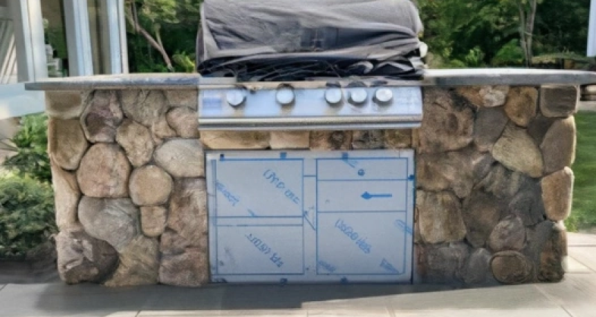 Exquisite outdoor kitchen crafted with New England Round Wallstone at a beautiful house in Hyannisport, Massachusetts, featuring a built-in grill, stone countertops, and a cozy dining area.